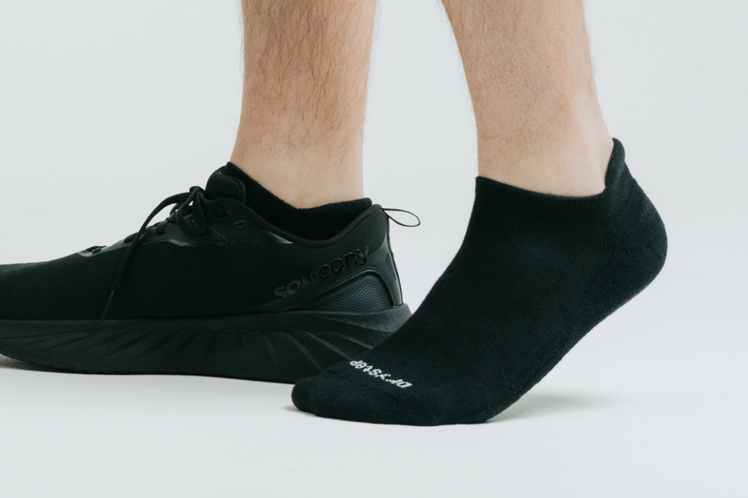 Man wearing black DryStep Ankle Tab socks, one foot in a black Saucony running shoe