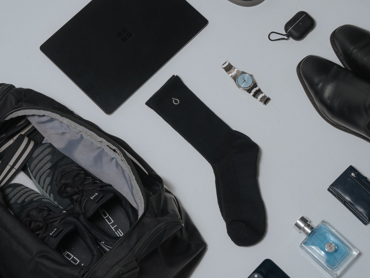 Black DryStep Crew sock laid flat with a gym bag, trainers, laptop, watch and leather boots