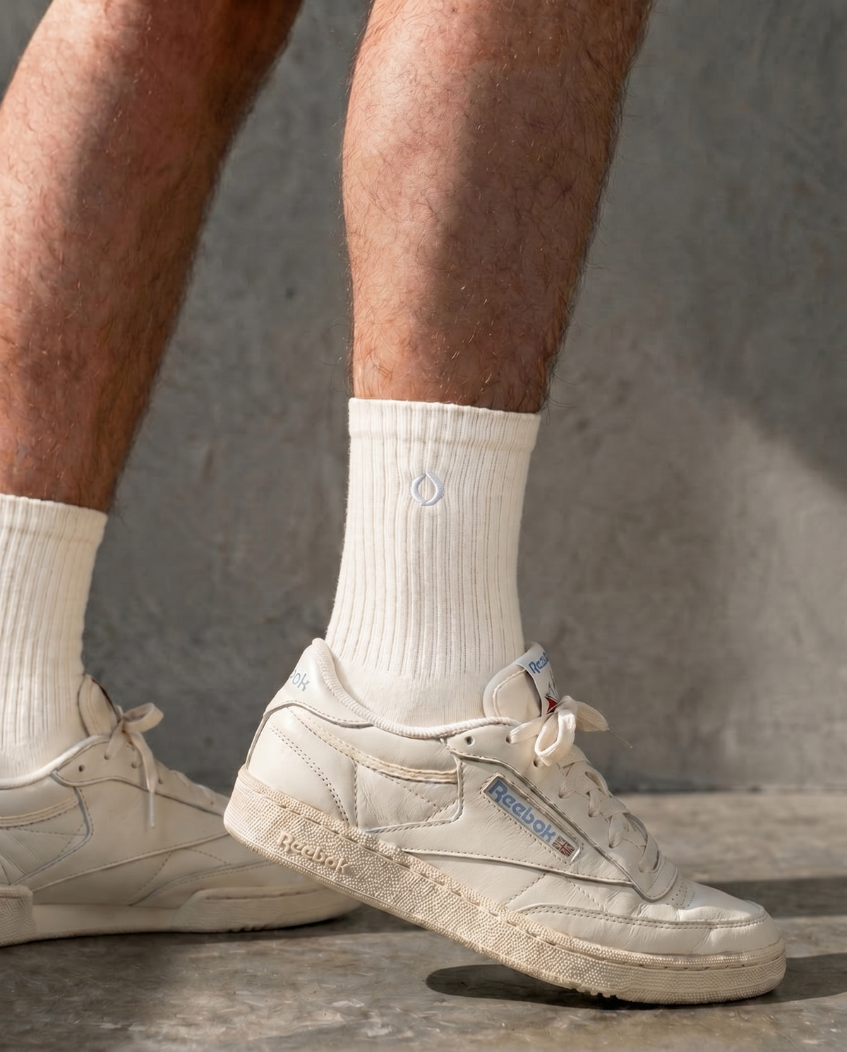 White reebok sneakers with vanilla mid-crew DryStep socks on a concrete floor