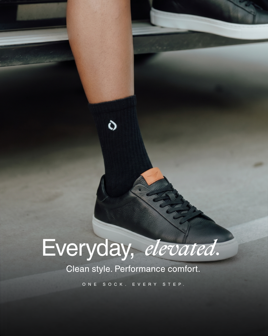 Black mid-crew sock worn with black leather sneakers
