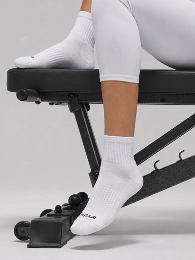 Woman wearing DryStep white quarter socks on a gym bench — lightweight sweat-wicking sock