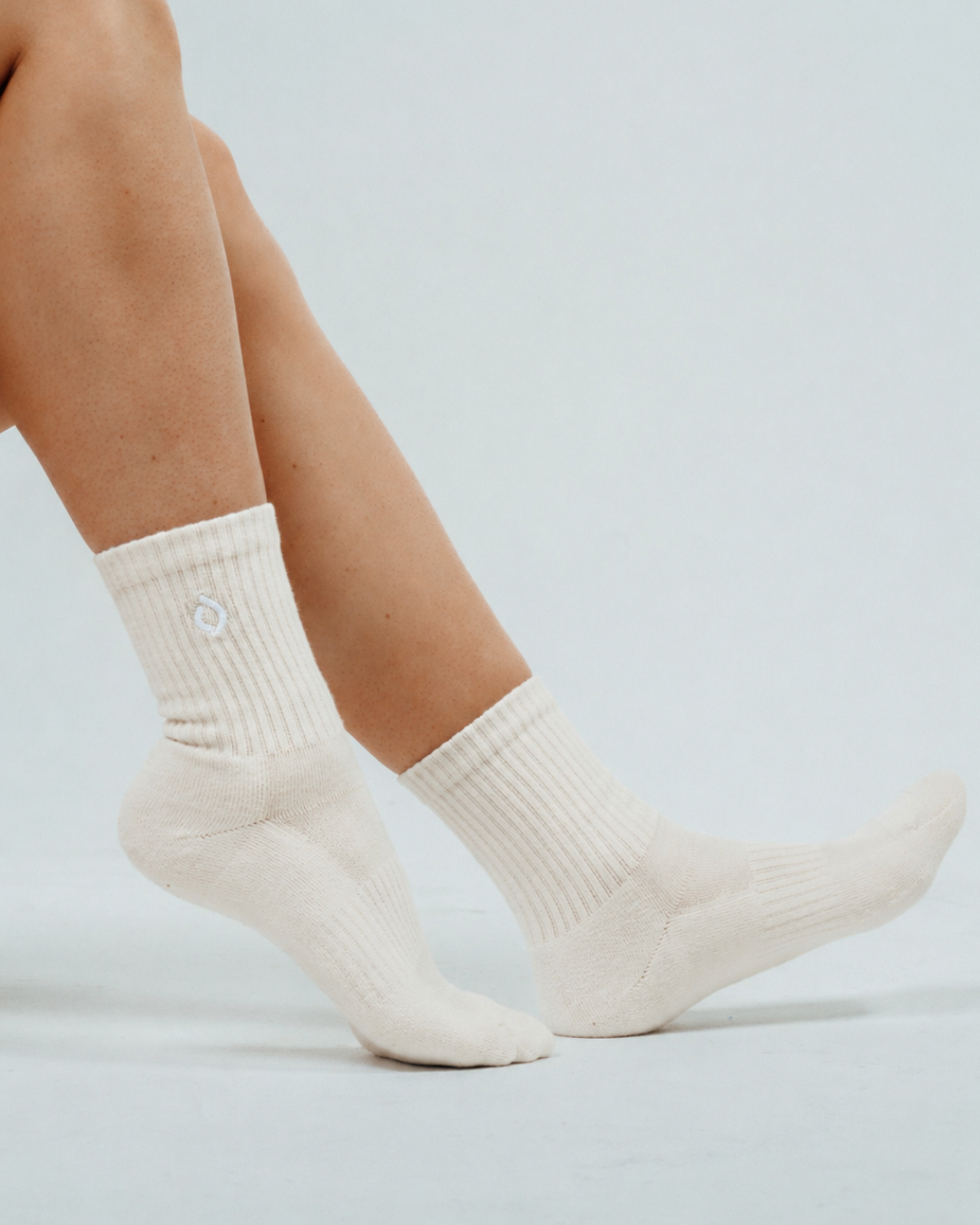 Woman wearing vanilla mid-crew socks in a studio shot