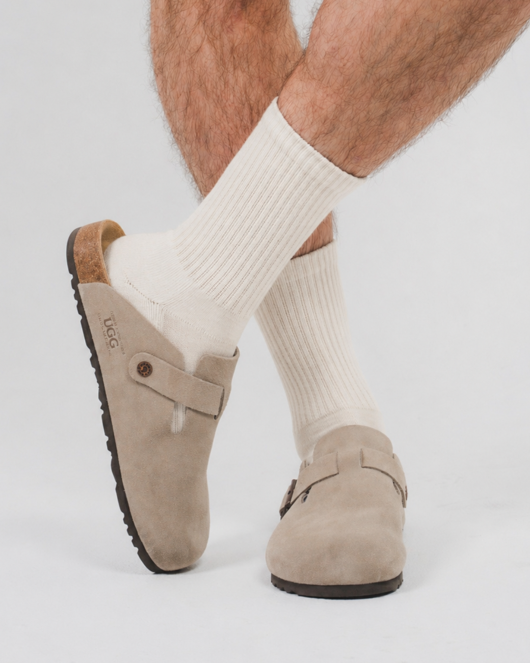 Beige suede clogs worn with vaniall mid-crew DryStep socks on a light gray background